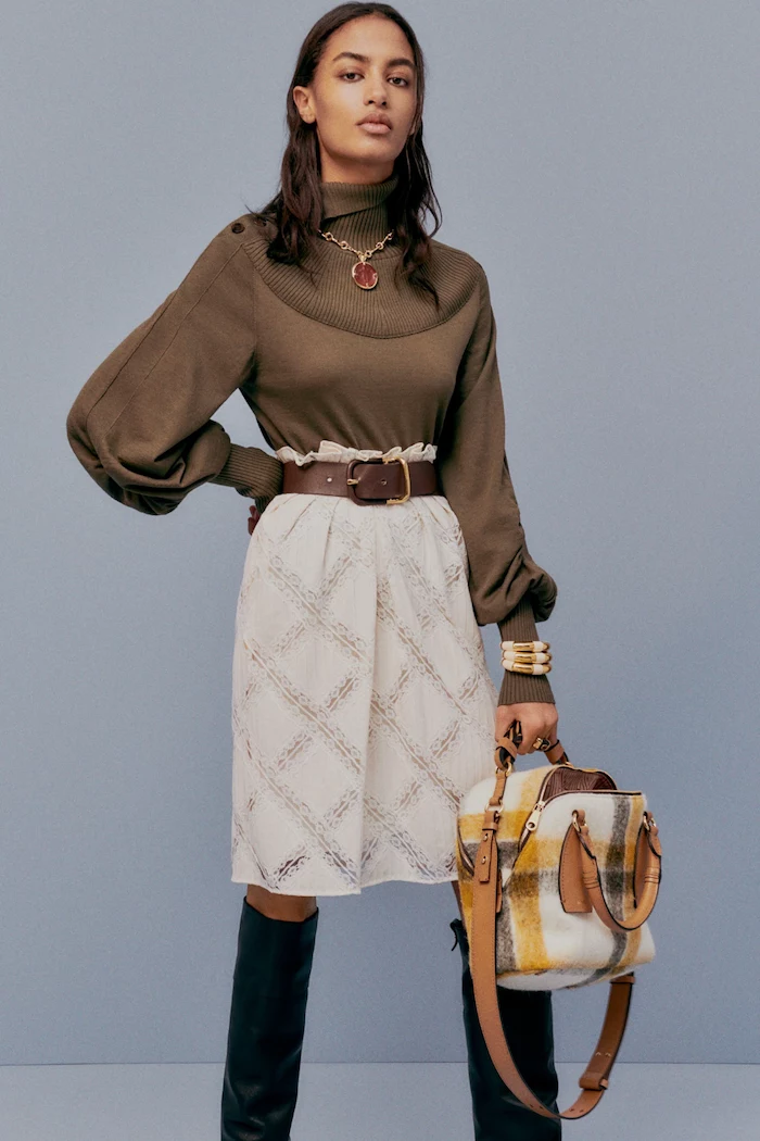cute outfit ideas for girl brunette woman wearing brown polo blouse white skirt with brown leather belt black leather boots
