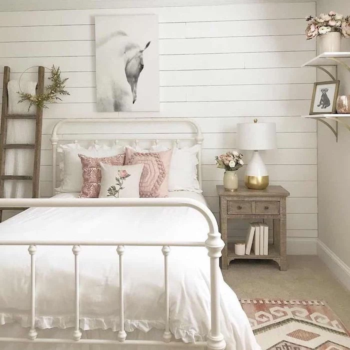 cute room ideas white wooden wall with art hanging above the bed rustic decor bed side table small ladder pink throw pillows on the bed