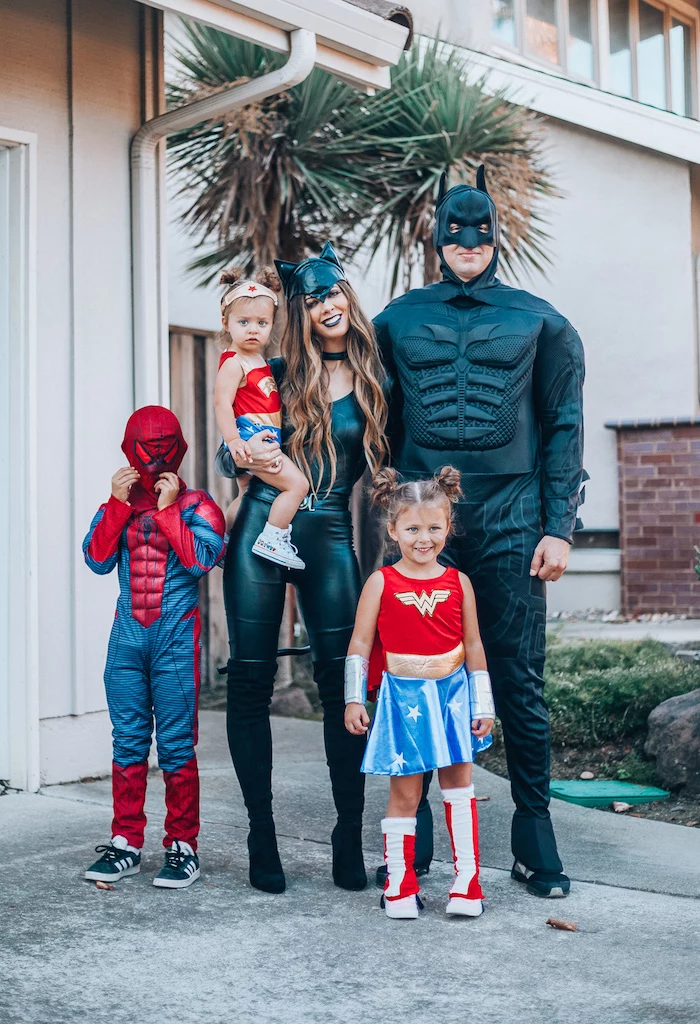 family of 4 halloween costumes mom and dad dressed as batman cat woman kids dressed as wonder woman spider man