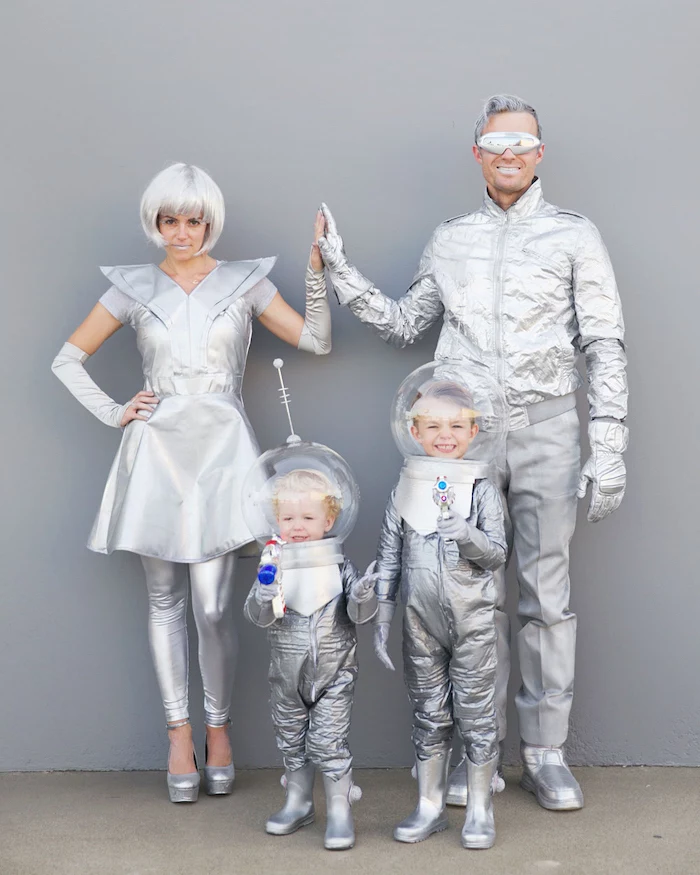 family of four dressed in all gray silver matching family halloween costumes space costumes photographed in front of gray wall