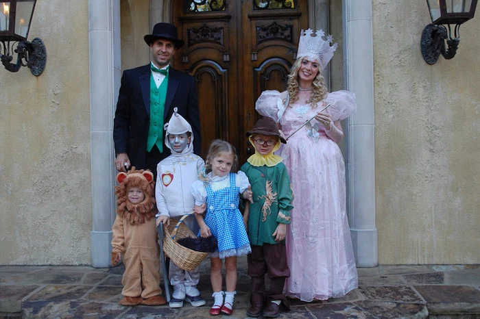 family of six dressed as characters from the wizard of oz family of 4 halloween costumes photographed in front of large wooden door