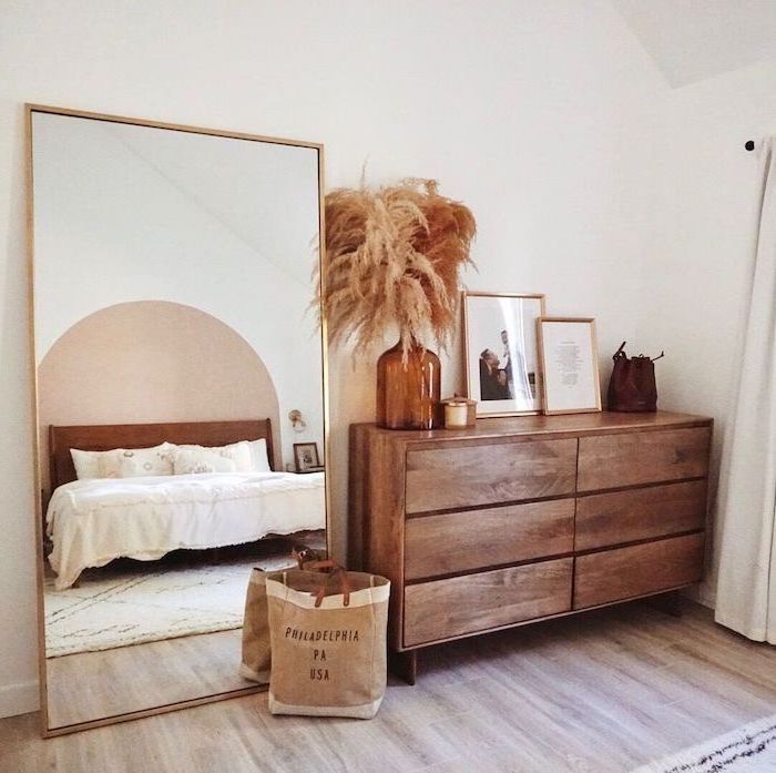 faux pampas grass wooden cupboard with framed art vase with pampas grass on top next to large mirror