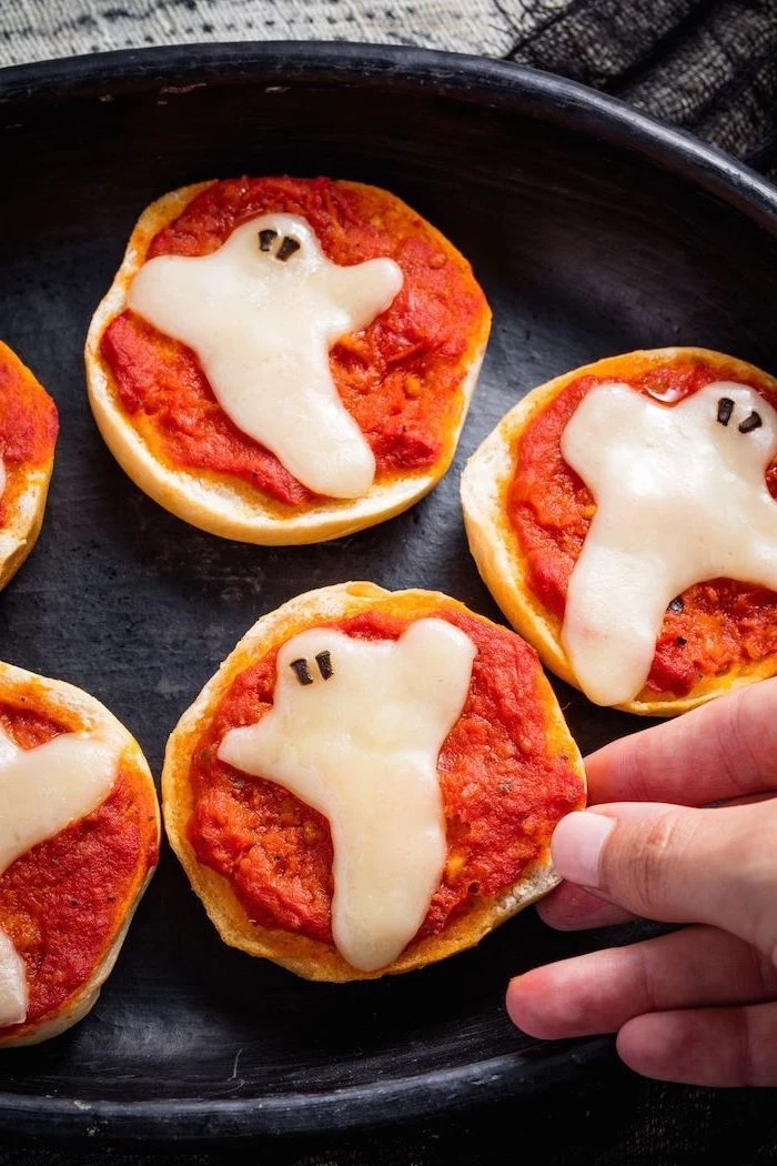 halloween finger foods mini bread bites with salsa cheese in the shape of ghosts baked in black pan