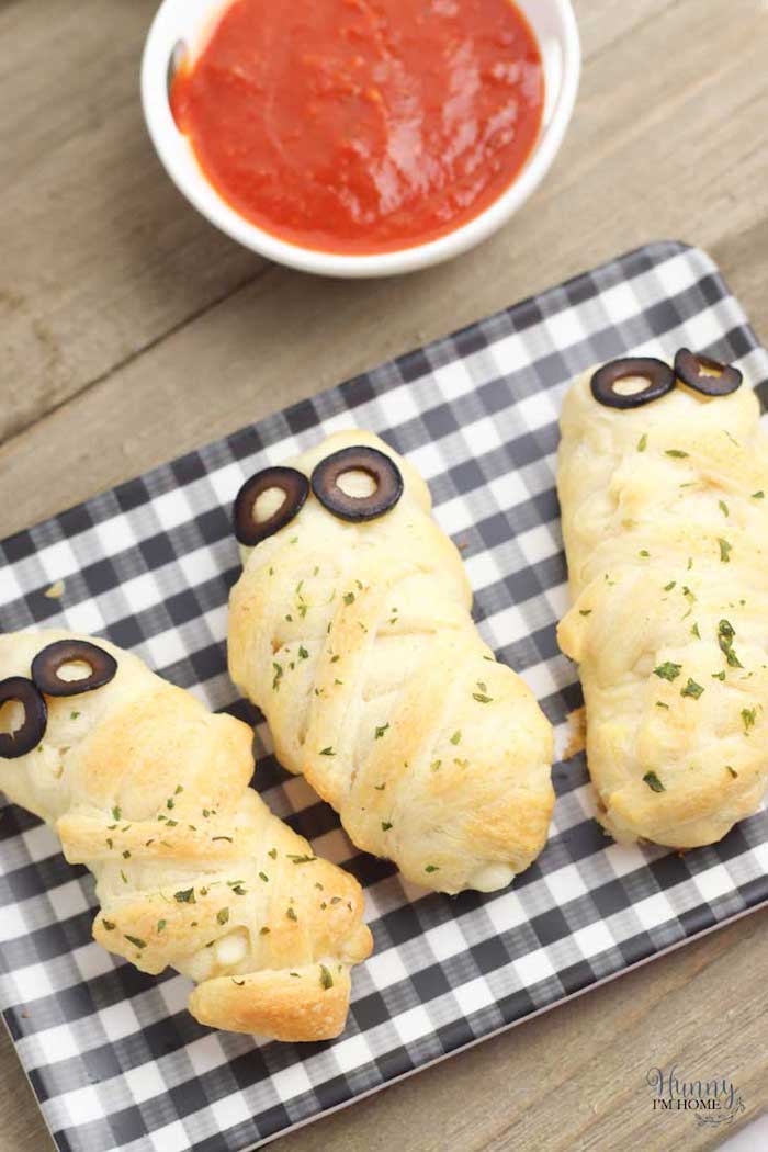 halloween party food for adults breadsticks wrapped with dough baked with olives for eyes salsa dip on the side