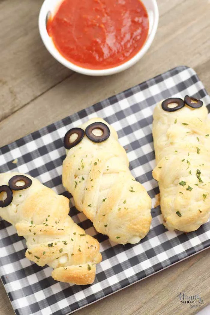 halloween party food for adults breadsticks wrapped with dough baked with olives for eyes salsa dip on the side