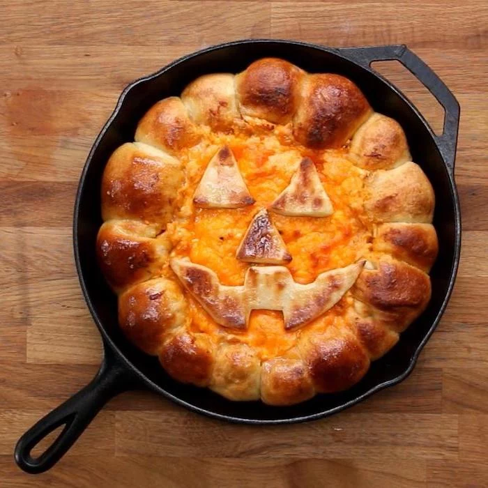 halloween snack ideas bread with melted cheese in the middle baked in black iron skillet placed on wooden surface