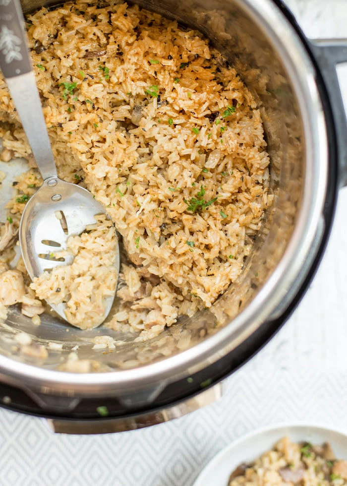 healthy instant pot recipes fried rice with chicken inside and instant pot stirred with large metal spoon placed on white surface