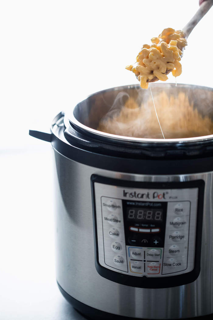 healthy pressure cooker recipes mac and cheese cooked in instant pot scooped with a wooden spoon white background