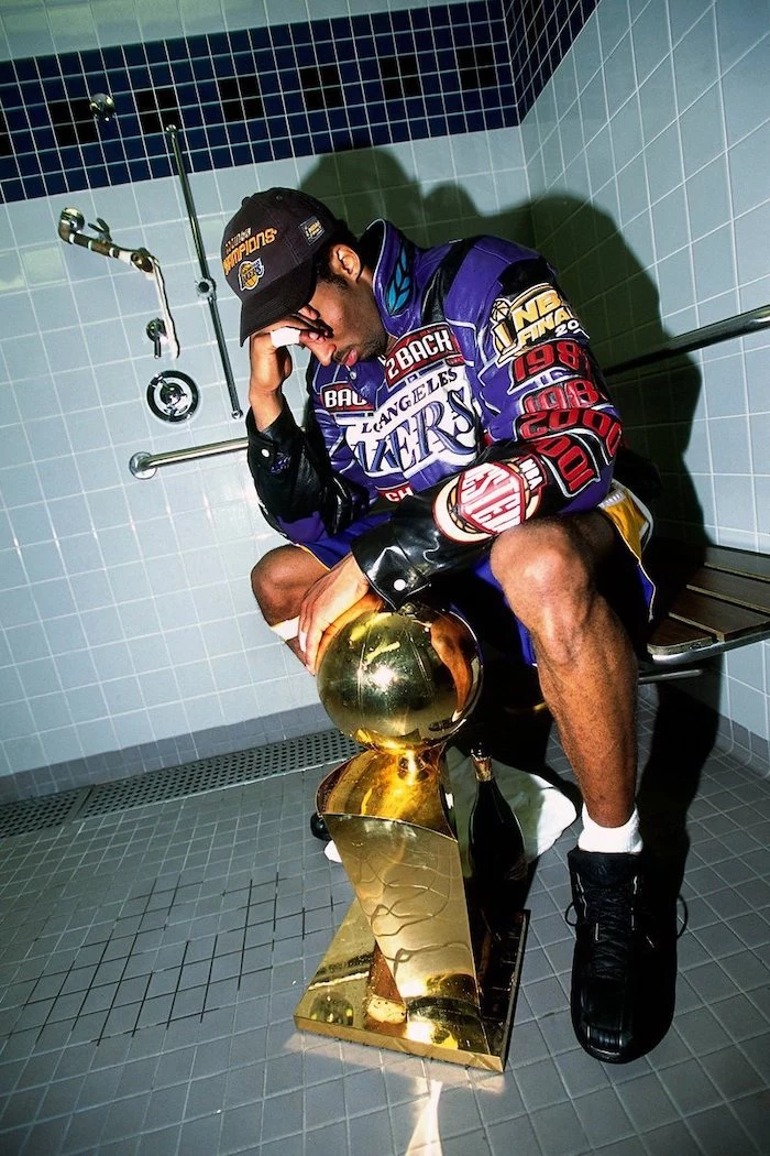 kobe sitting on a bench under showers cool kobe bryant wallpapers championship trophy on the floor in front of him wearing purple jacket