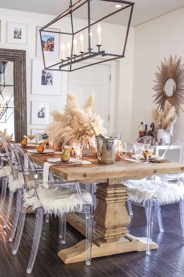 large wooden dinig table with plastic chairs colored pampas grass arrangement in the middle thanksgiving decoration