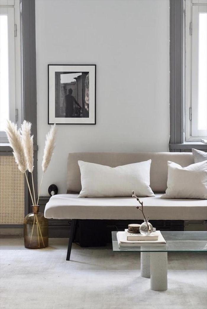 living room with white sofa glass coffee table brown glass vase with colored pampas grass inside white carpet