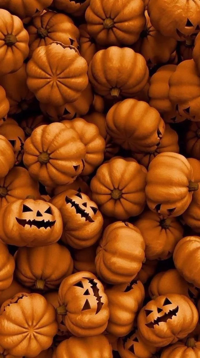 lots of pumpkins gathered together with carved spooky faces halloween phone wallpaper
