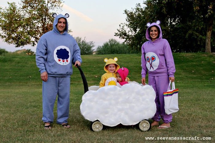 mom and dad sitting next to cart on wheels decorated as a cloud diy family halloween costumes kids inside