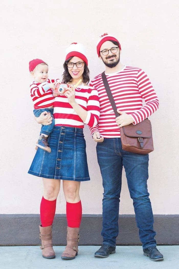 mom dad and baby dressed as waldo from wheres waldo family of 4 halloween costumes photographed in front of white wall