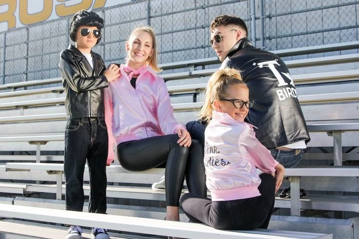 mom dad and two kids sitting in the bleachers family of 4 halloween costumes dressed as characters from grease