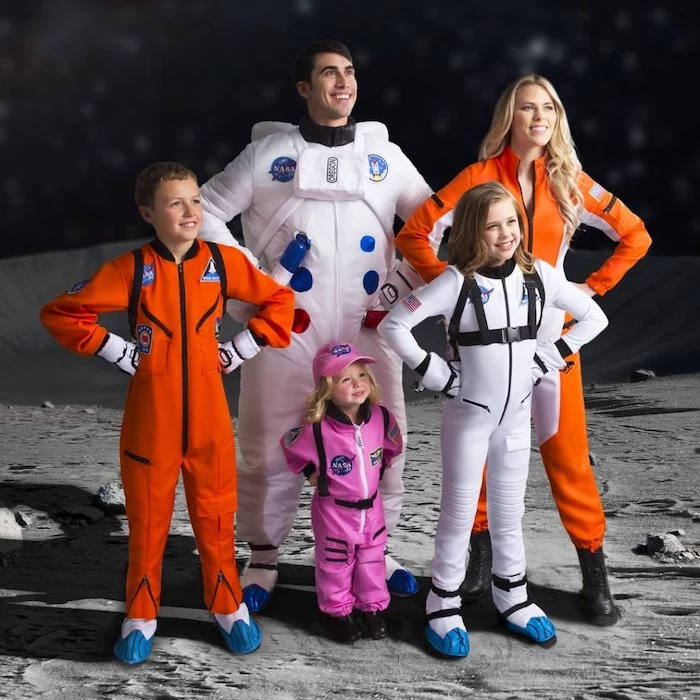 mom dad three kids dressed as astronauts photographed on background looking like the moon family of 3 halloween costumes