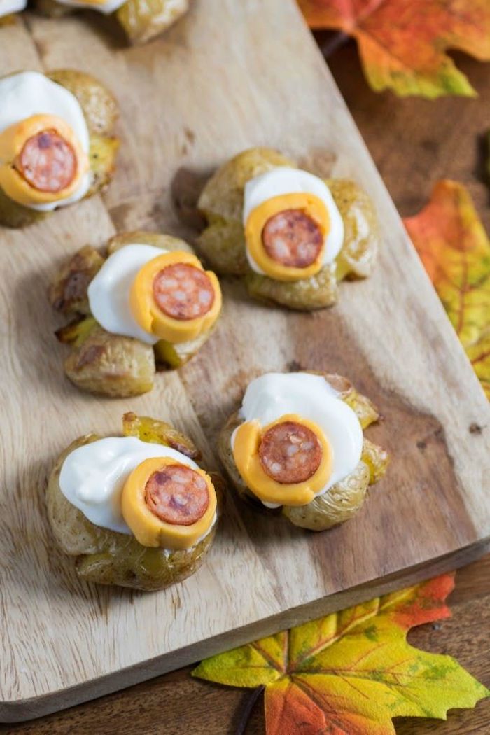 monster eye balls made with potatoes cheese and sausage halloween appetizer ideas arranged on wooden cutting board