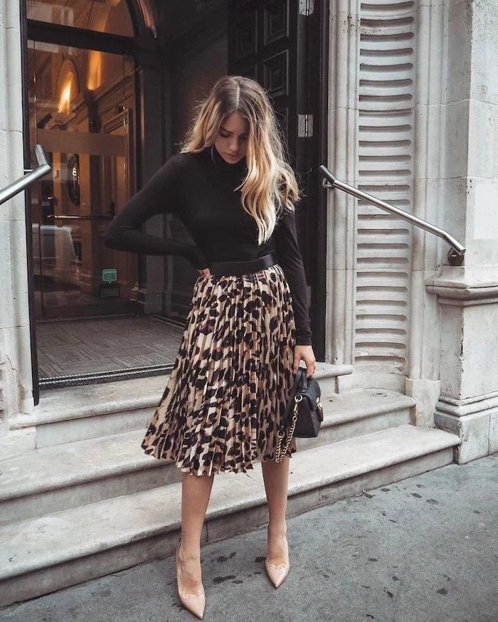 outfit ideas for women woman with long blonde wavy hair wearing leopard print pleated dress black blouse small bag