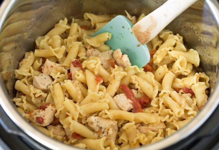 pasta chopped chicken breast sun dried tomatoes placed inside instant pot bowl best pressure cooker recipes stirred with silicone spatula