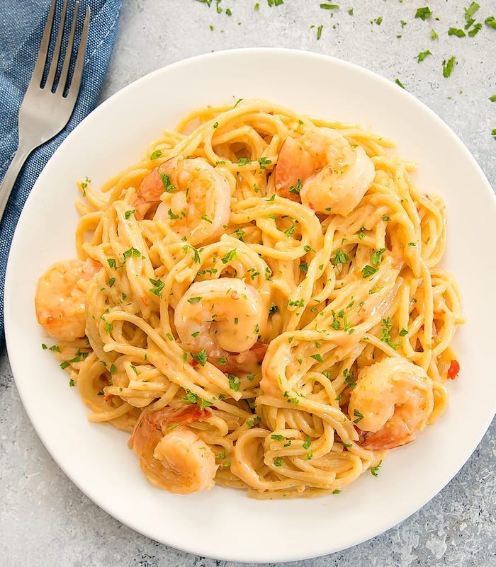 pasta with creamy sauce and shrimp garnished with chopped parsley instant pot recipes inside white plate