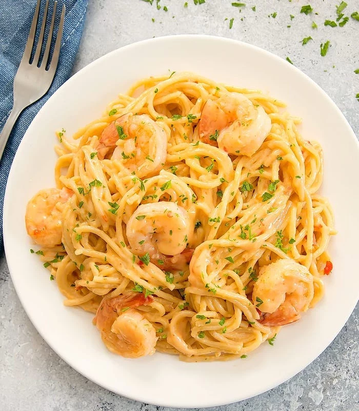 pasta with creamy sauce and shrimp garnished with chopped parsley instant pot recipes inside white plate