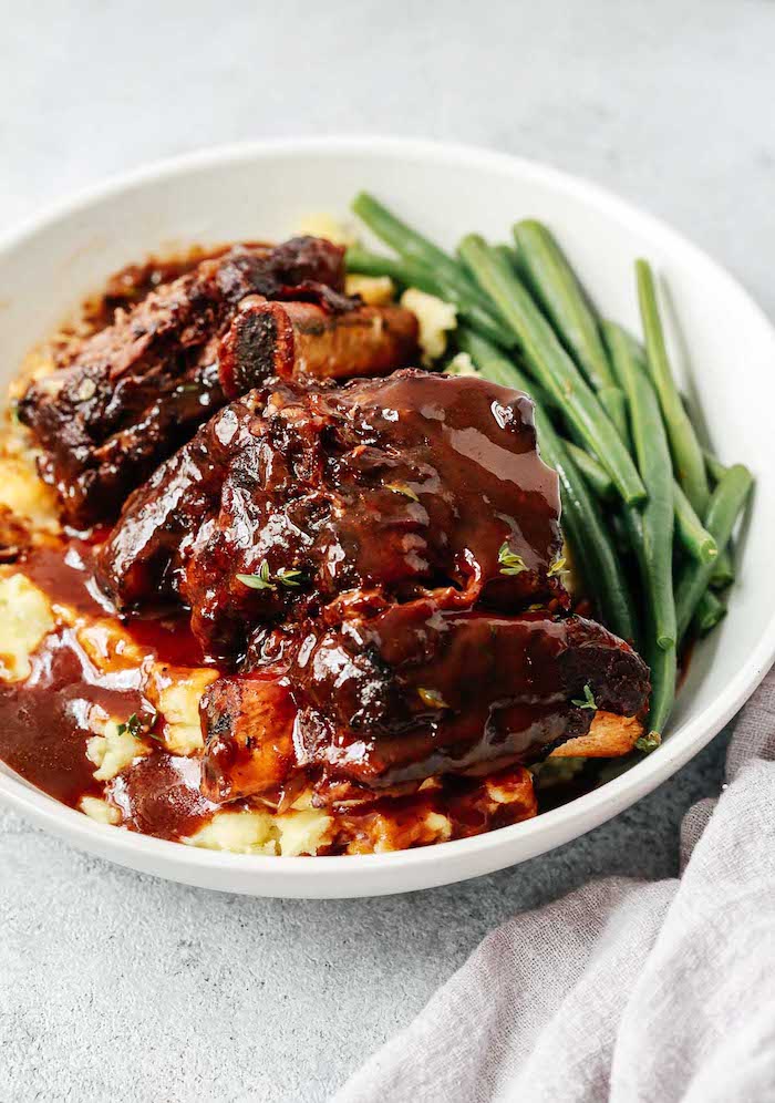 short ribs with creamy dressing best instant pot recipes placed on top of mashed potatoes peas in white plate