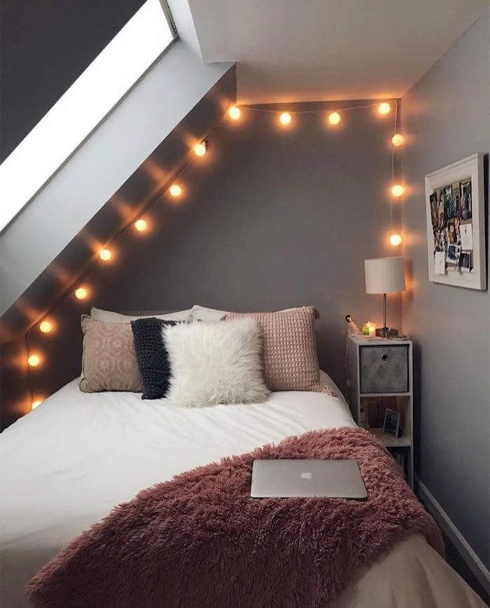 teenage girl bedroom ideas gray walls bed with pink fluffy blanket pink throw pillows fairy lights on gray walls