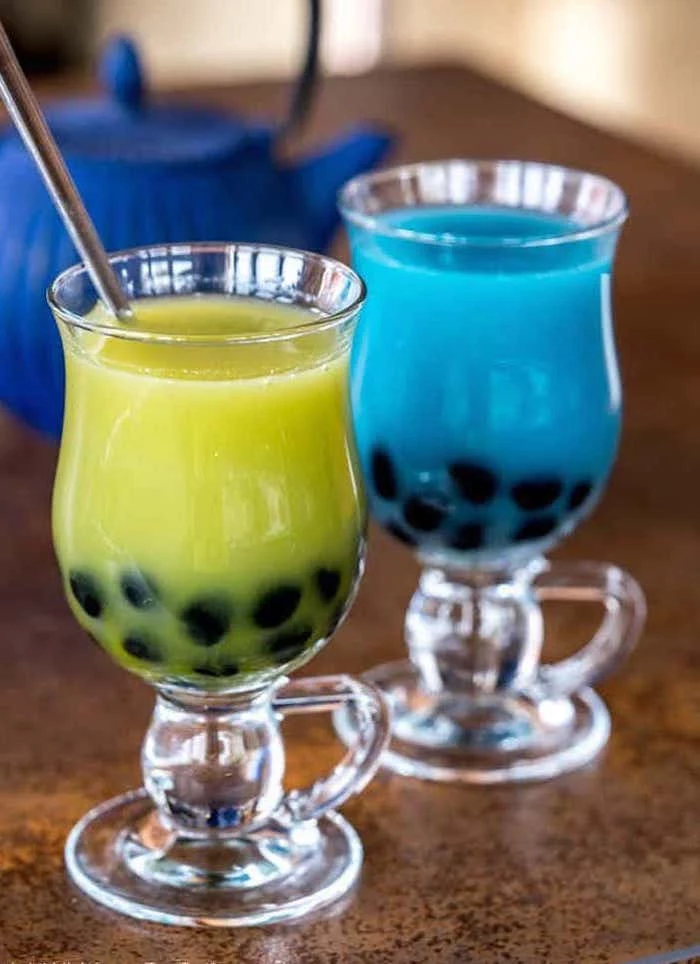 two glasses with green and blue bubble tea steel straw how to make boba placed on brown granite surface