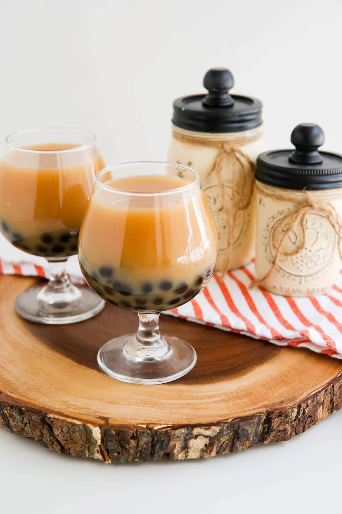 two glasses with keto bubble tea how to make boba tea tapioca pearls on the bottom of the glasses placed on wooden log