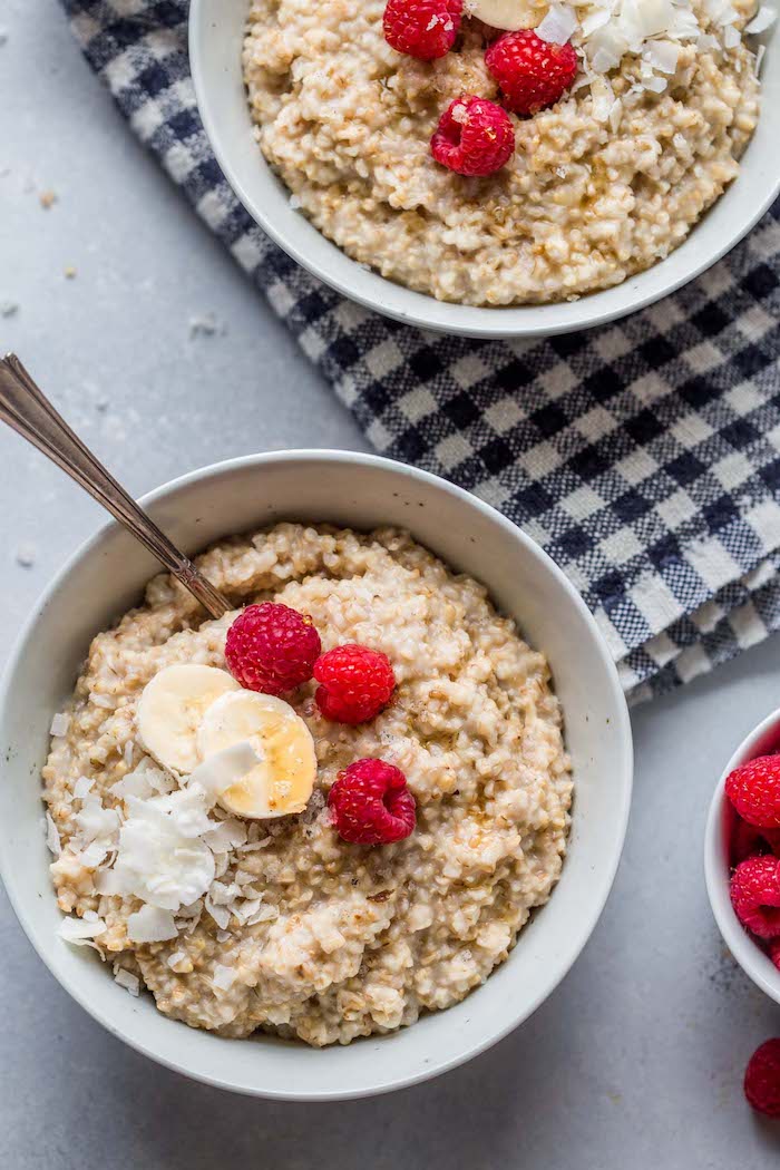 two white bowls with oatmeal cooked in instant pot healthy pressure cooker recipes with bananas raspberries shredded coconut