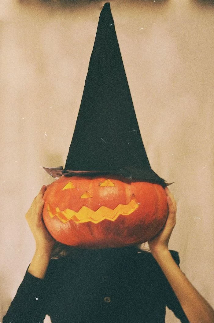 vintage photo of woman dressed in a witch costume halloween desktop wallpaper carved pumpkin in front of her face witch hat on top of ther head