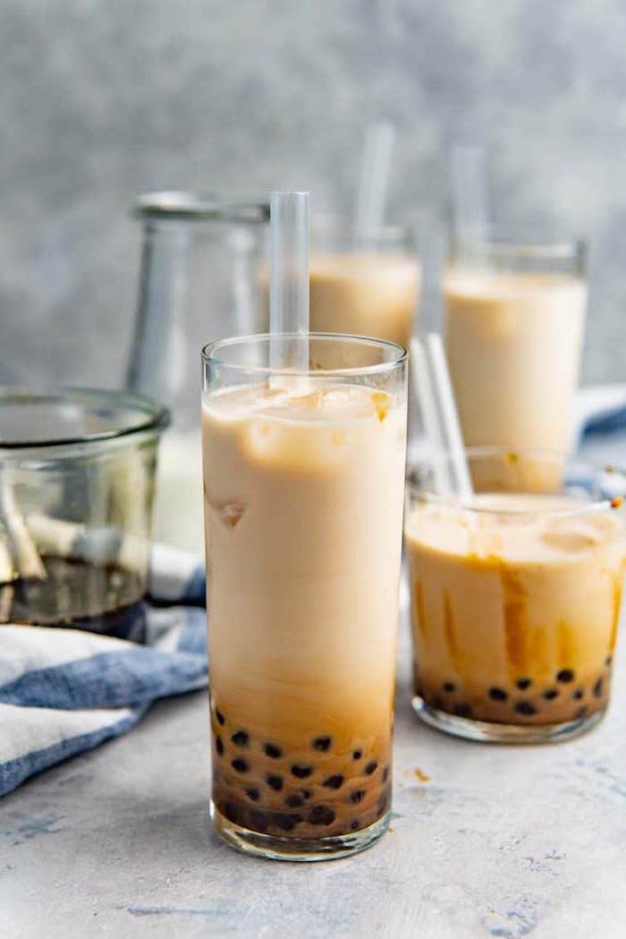 what is boba tall glass with bubble tea plastic straw inside more glasses arranged on the table in the background
