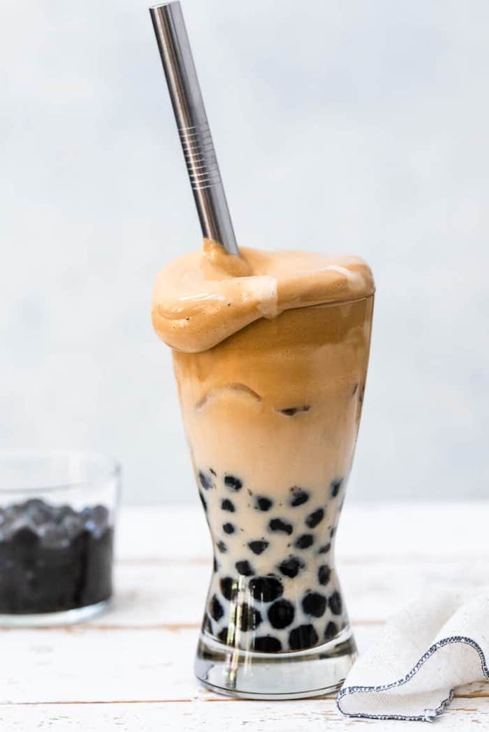 what is boba tea dalgona coffee made with tapioca pearls spilling out of tall glass with steel straw