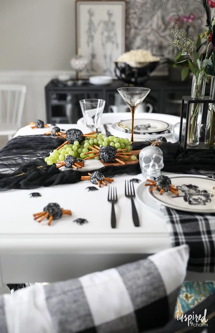 white table decorated with black tulle halloween party appetizers wooden cutting board with spider cheese balls grape