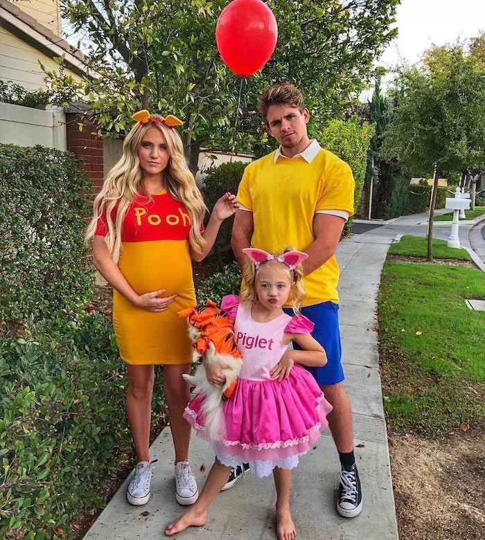 winnie the pooh piglet and christopher robin family halloween costume ideas family standing on sidewalk mom pregnant holding red balloon