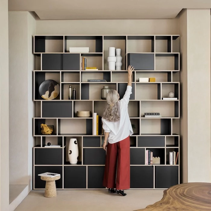woman reaching opening a cabinet on black wooden bookshelf bookcase ideas shelves in different shapes