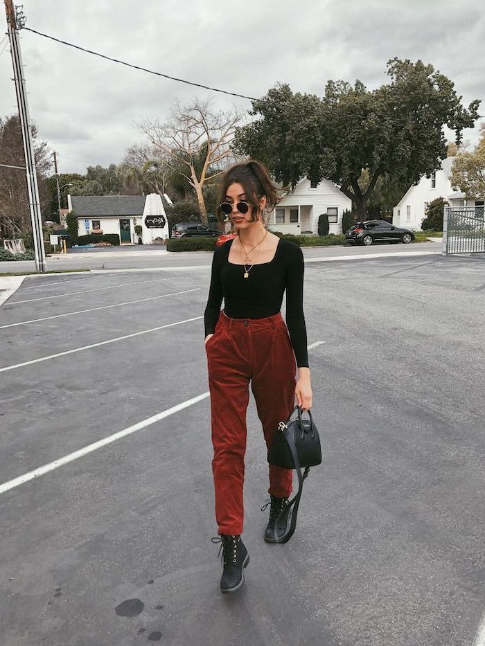 woman wearing red trousers black boots black top and bag fall dresses for women black hair in high ponytail