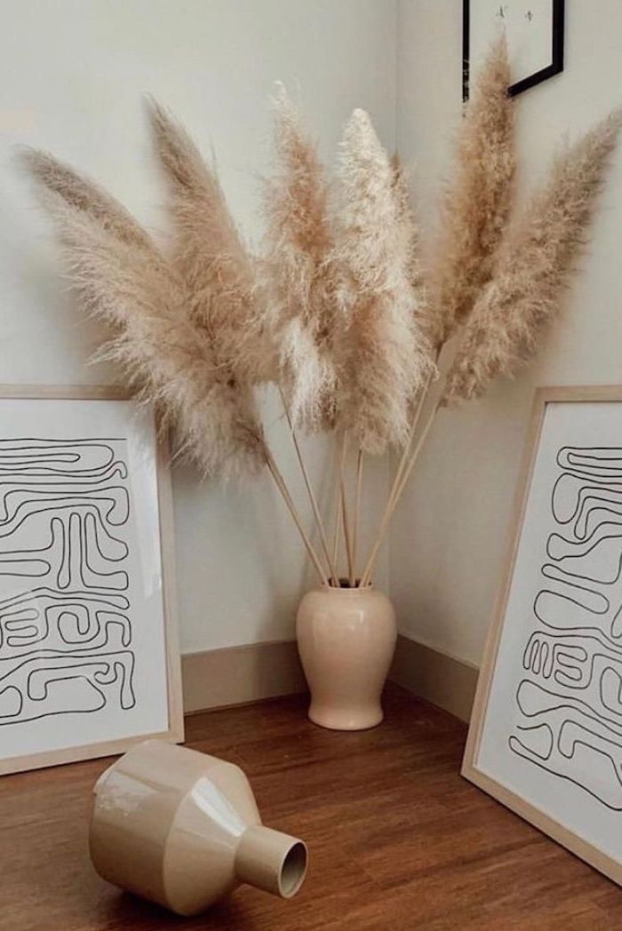 wooden floor and white wall ceramic vase with artificial pampas grass framed art next to it leaning on the wall