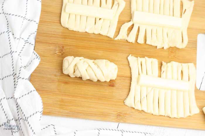wrapping the cheese in dough halloween party food for adults placed on wooden cutting board white table cloth