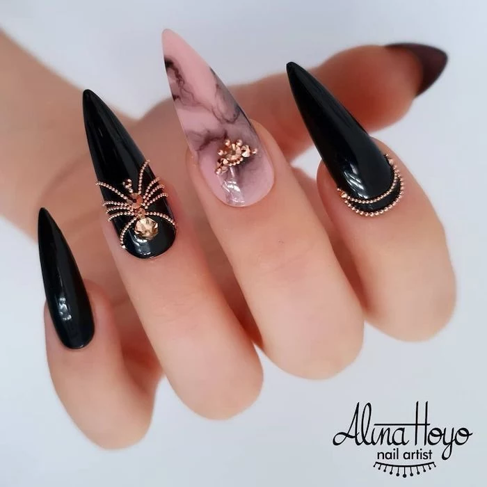 acrylic nail ideas long stiletto nails black nail polish with spider shaped rhinestones pink and black marble on middle finger