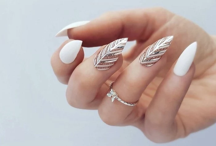 almond shape with pointed ends cute acrylic nail ideas white nail polish gold and silver feather decorations on middle and ring fingers