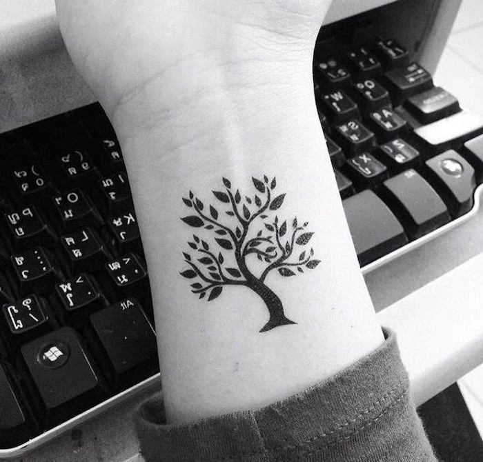 black and white photo of tree of life wrist tattoo tattoos that mean strength keyboard in the background