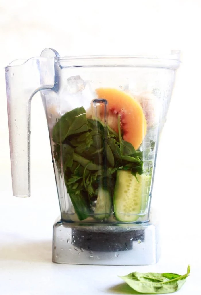 blender jug filled with ingredients best detox cleanse for weight loss cucumber peach spinach parsley