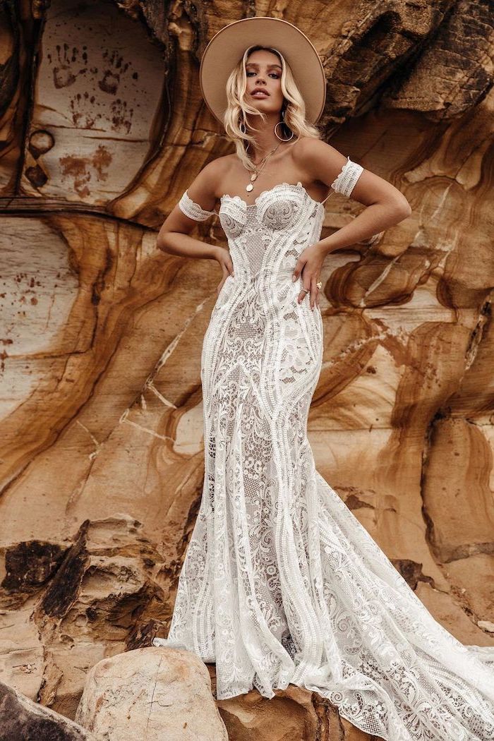 https://archziner.com/wp-content/uploads/2020/10/blonde-woman-wearing-all-lace-dress-with-heart-shaped-neckline-bohemian-wedding-dress-wearing-a-baige-hat-standing-on-rocks.jpg