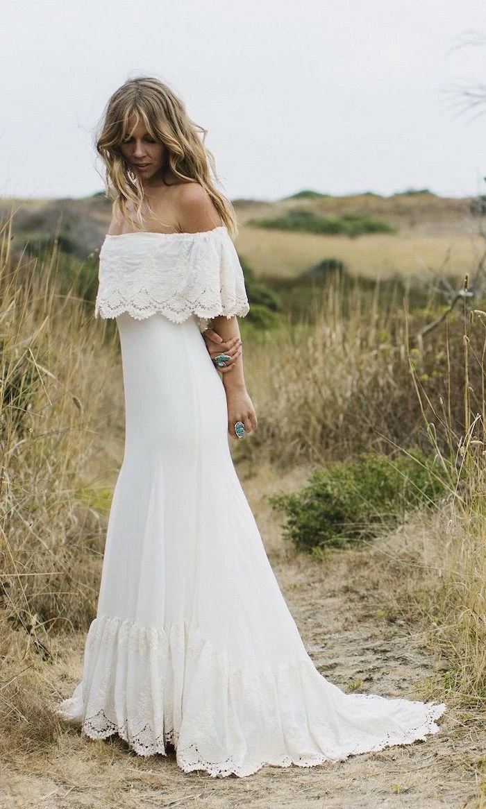 blonde woman with long wavy hair wearing long white bohemian wedding dress with lace on the bottom and lacy flounce