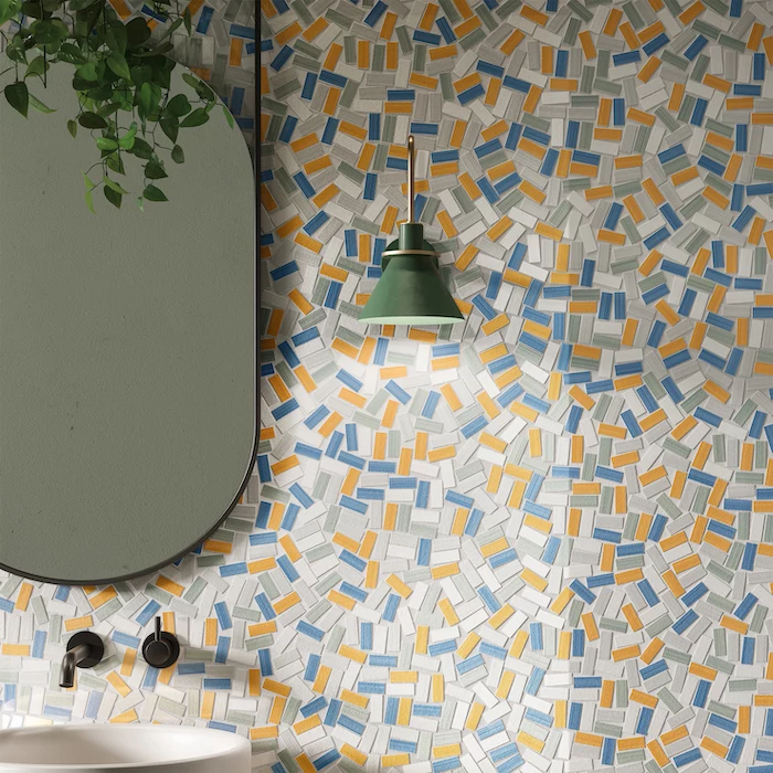 blue gray orange white mosaic tiles on wall with mirror hanging on it above sink floor tiles green lamp