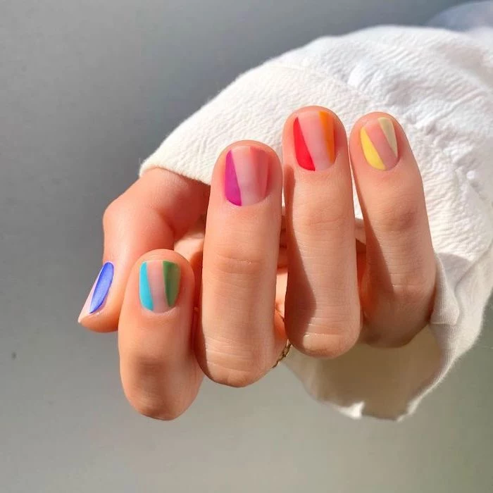 blue green pink orange yellow geometrical nail polish on nude short squoval nails almond shaped nails