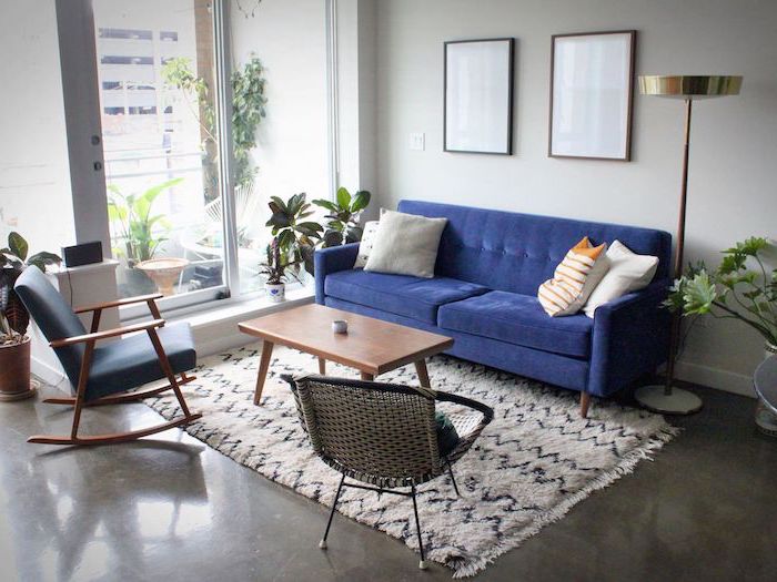 blue velvet sofa with white throw pillows blue rocking chair mid century living room wooden coffee table on white carpet