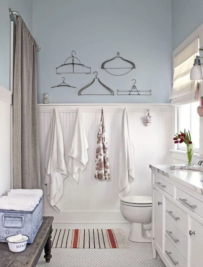 blue walls on top white shiplap on the bottom farmhouse bathroom tile white mosaic floor white vanity with marble countertop