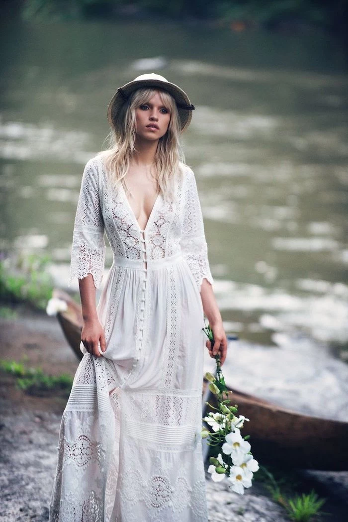 bohemian style wedding dresses blonde woman with bangs wearing all lace dress with buttons at the front hat holding white flower bouquet